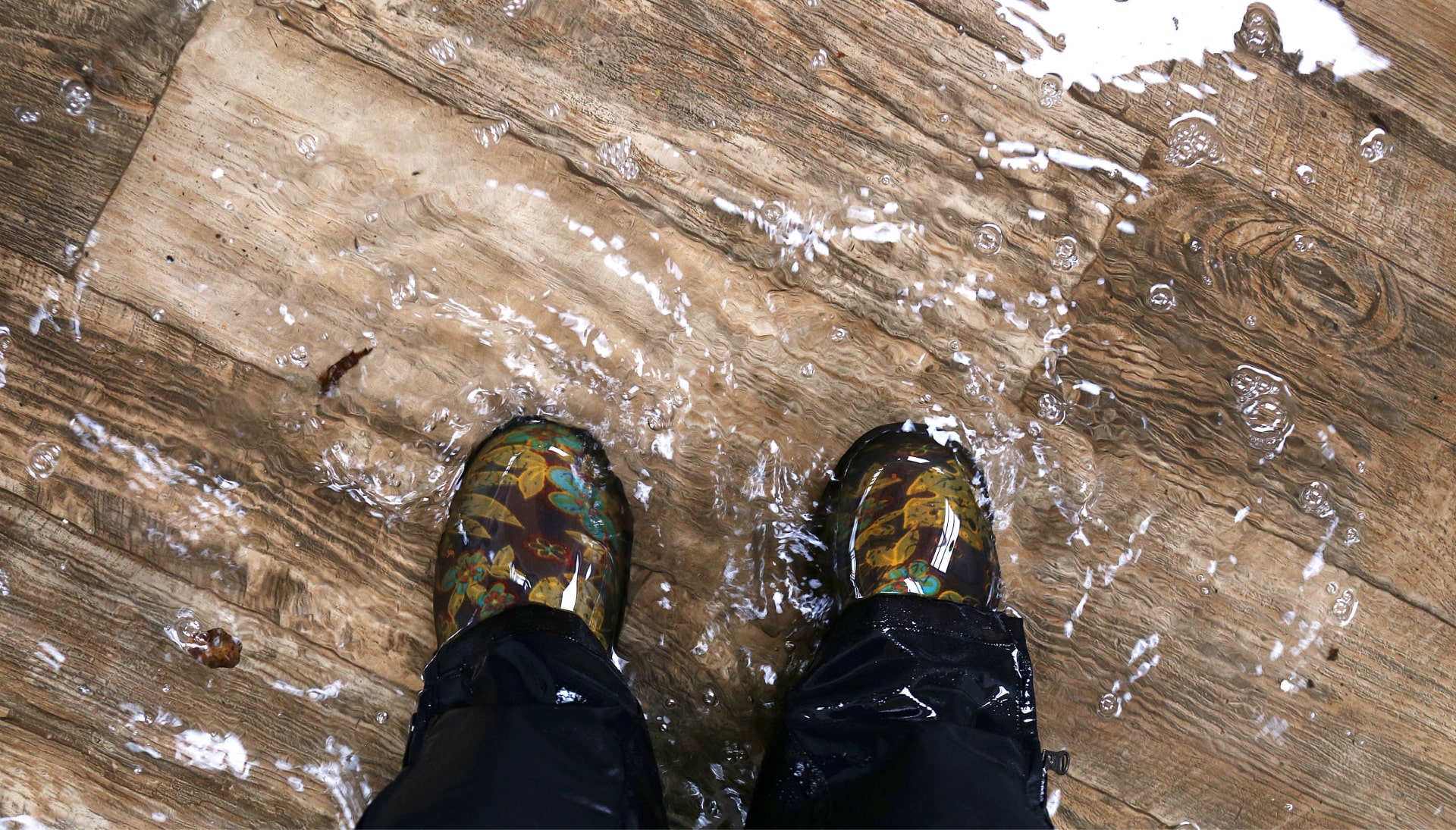 Homeowner walks through flood waters wearing rain boots as they await water damage cleanup in Billings, MT.